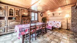 Un interior de madera con una mesa de comedor, sillas, un sofá y una araña.