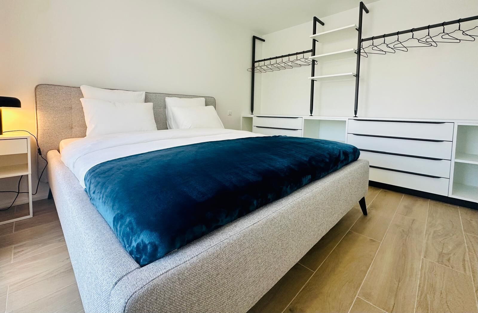 Quarto moderno com cama, mesa de cabeceira, guarda-roupa e estante embutida.