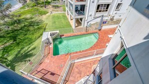 A rooftop pool with a clear view of the surrounding landscape, including a grassy area and a building with a balcony. - Shoreline Apartments - Unit 15 (Bargara)