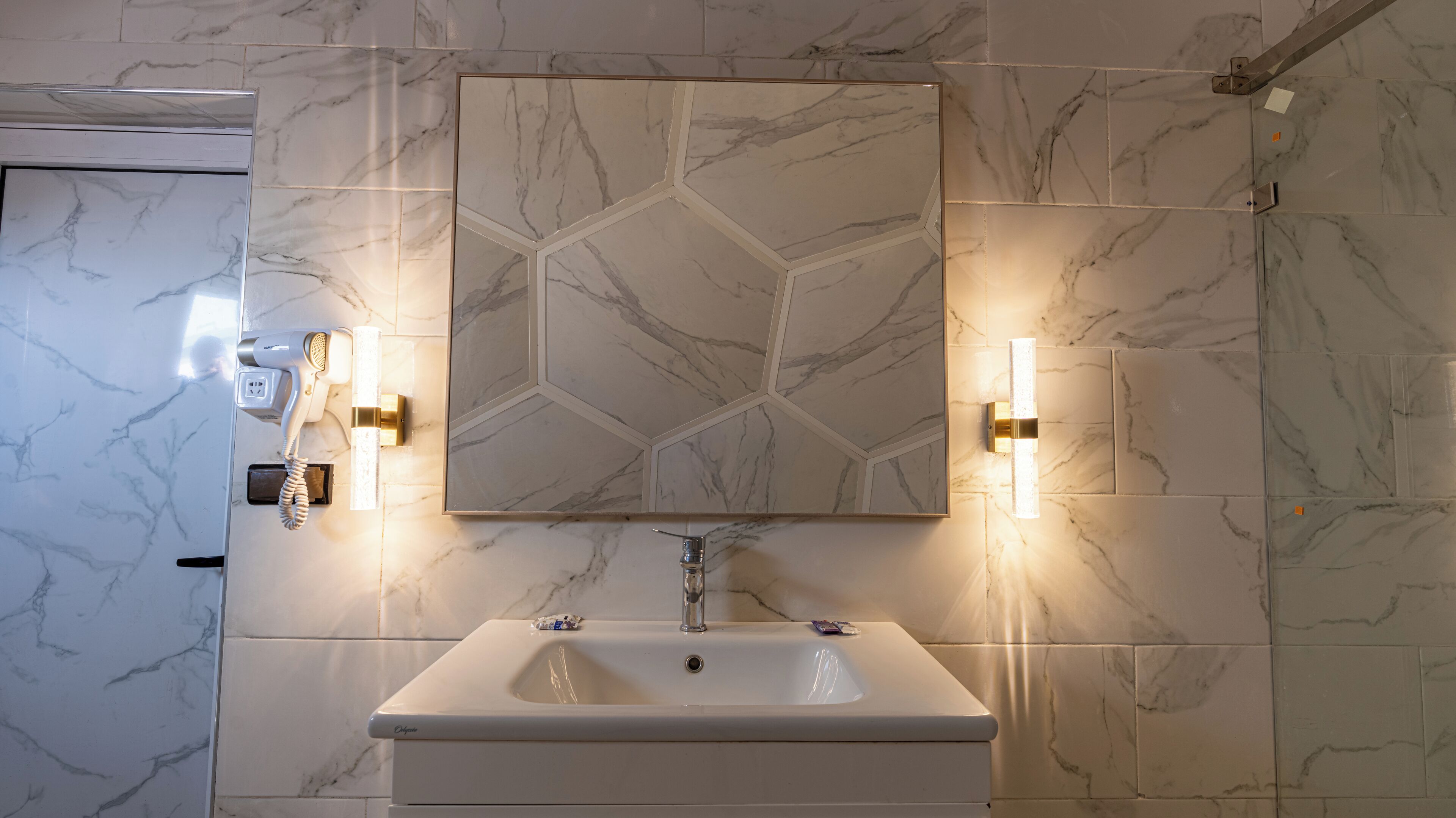 Een badkamer met een witte wastafel, een spiegel en twee wandlampen.