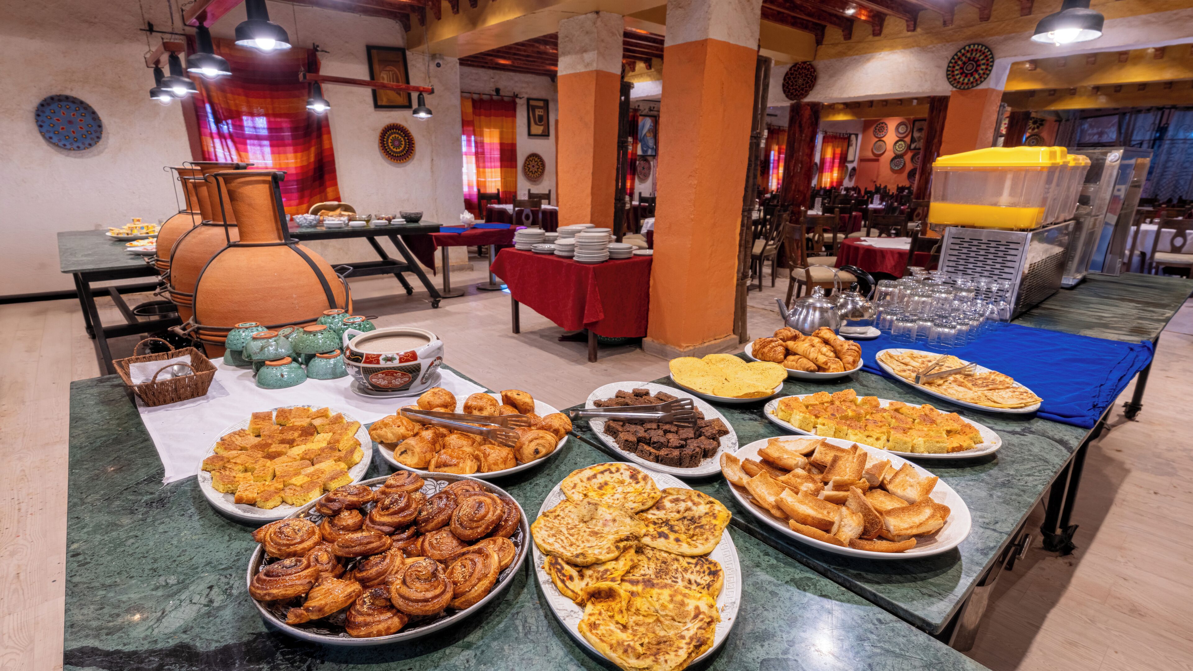 Un bufé con diversos platos, incluyendo pasteles, pan y postres.