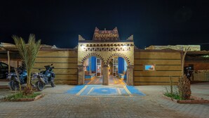 A reception area with a sign reading "AKM Reception" and two motorcycles parked outside. - Kasbah Merzouga (Taouz)