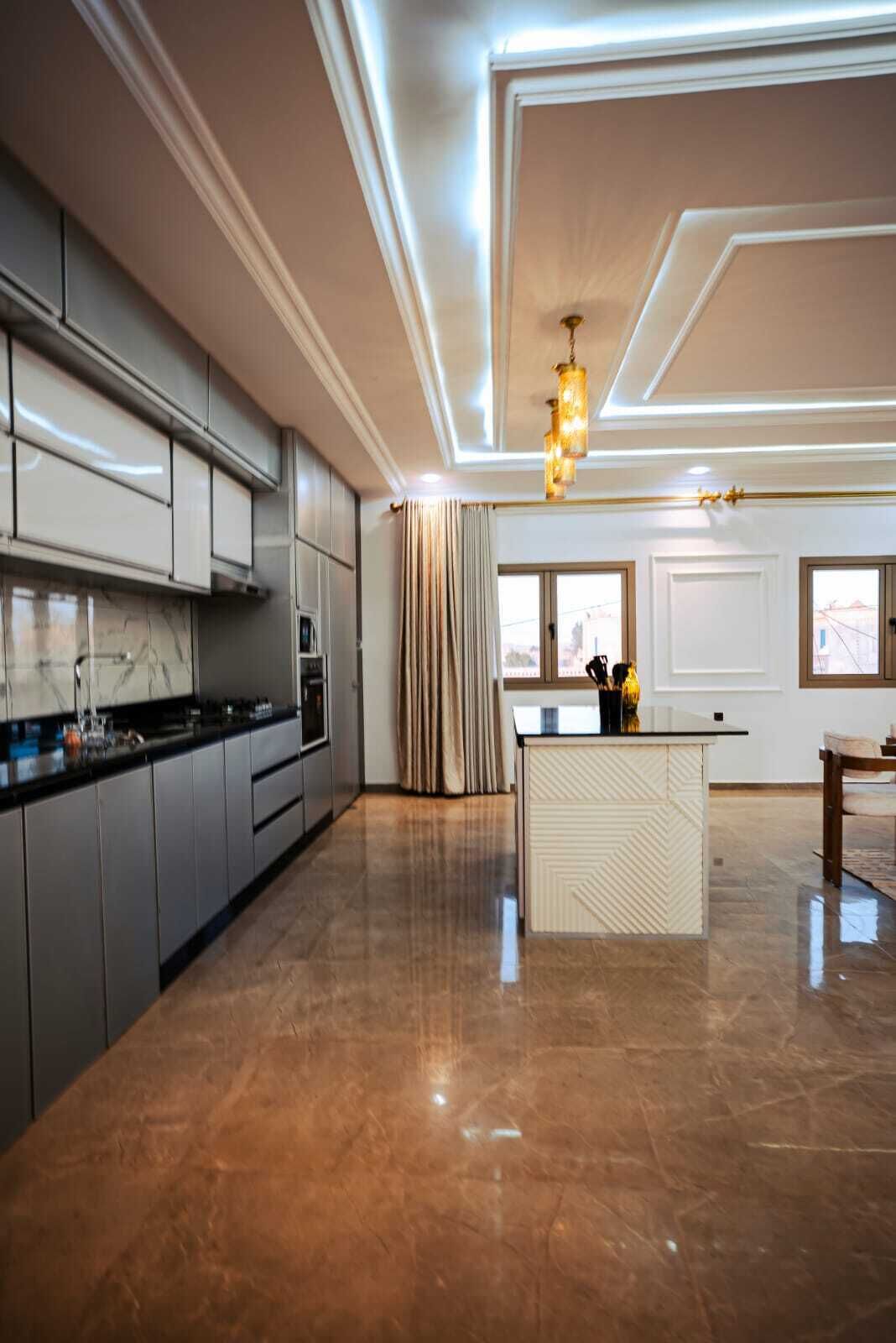 A spacious kitchen with a central island, modern cabinetry, and a polished floor.