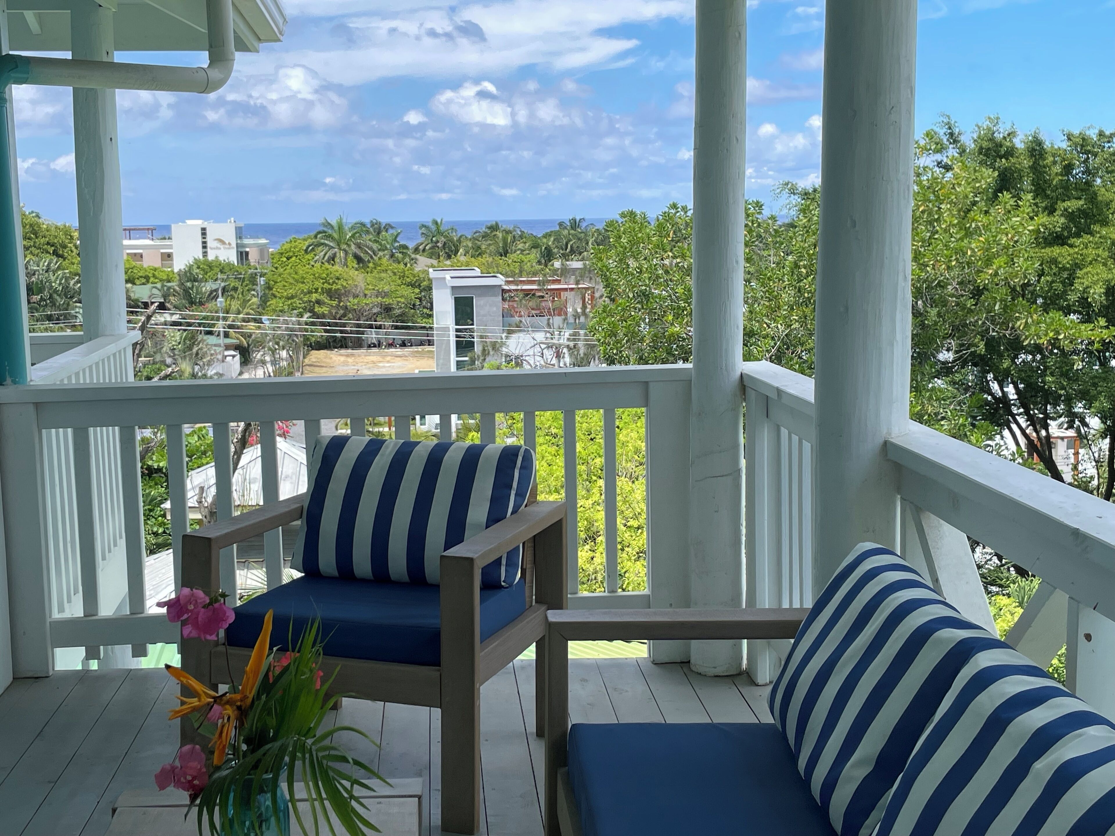 A wooden deck with a blue-striped sofa and a small table with a vase of flowers.