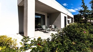 A modern building with a covered patio area featuring two chairs and a table.