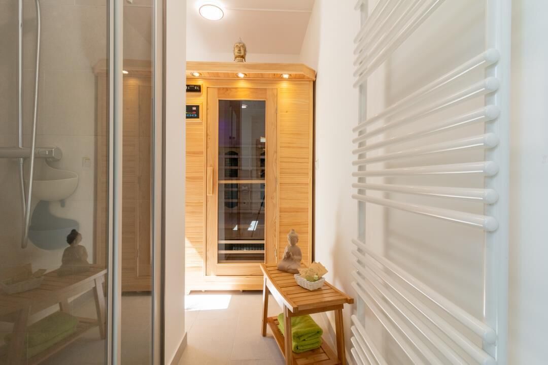 Ein Flur mit Sauna, einer Holzbank und einer Statue.