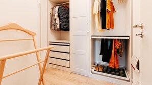 A walk-in closet with hanging space and drawers, containing various clothing items.
