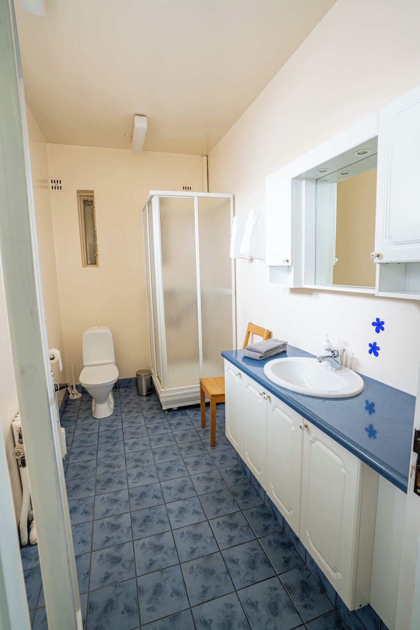 A bathroom with a toilet, a shower, a sink, and cabinets.