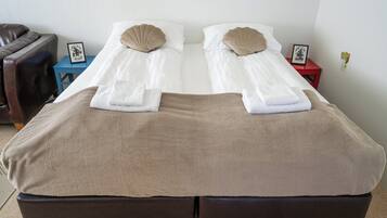 A double bed with two pillows, a brown blanket, and a small bedside table with a picture frame.
