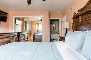 Un dormitorio con una cama grande, cabecera de madera, un aparador y un espejo.