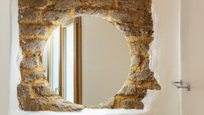 A circular mirror framed by a rough stone wall. - Ausentu Guest House (Tortoli)