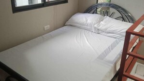 A single bed with white bedding in a room with a window and a metal-framed headboard. - 1 Bed House - Sleeps 2 - Parking - Wifi (Zamboanga)