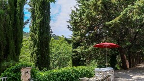A garden area with a gravel path, a red umbrella, and outdoor seating. - Le Prunier by Interhome (Oraison)