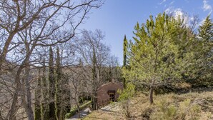 A rustic building with a wooden door, surrounded by trees and a gravel path. - La Chênaie by Interhome (Oraison)