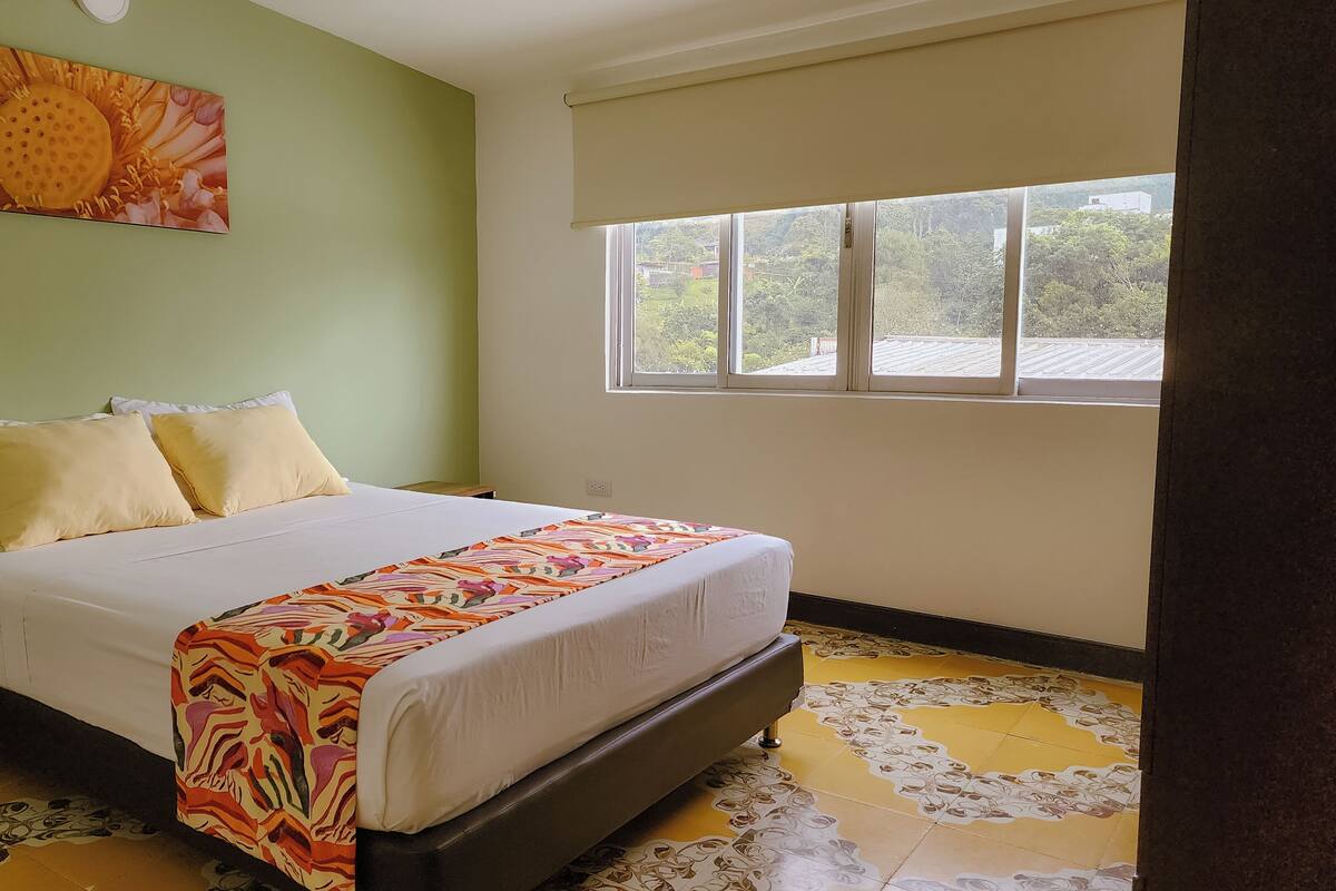 A bedroom with a bed, a window, and a green wall.