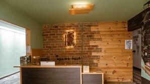 A reception area with a wooden counter, a brick wall, and a hanging light fixture. - Tuki Hostel & Lounge (Pereira)