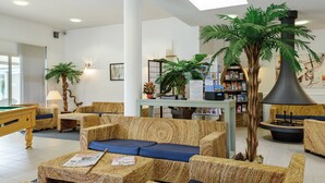 Een hal met rieten meubels, een pooltafel en een boekenkast.