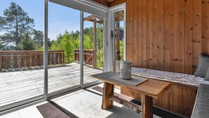 Un intérieur en bois avec une grande porte-fenêtre coulissante donnant sur une terrasse extérieure.