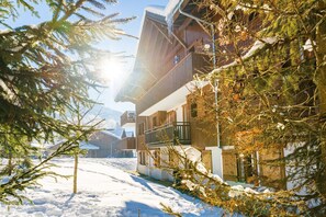 Un sendero cubierto de nieve que lleva a una cabaña de madera con balcón.