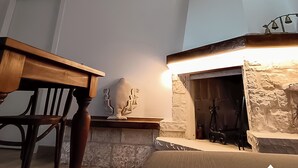 A room with a wooden table, a stone fireplace, and a ceiling light fixture. - The House on the Knoll-Valle d'Itria CIN:IT073013C200089627 CIS:TA07301391000050432 (Alberobello)
