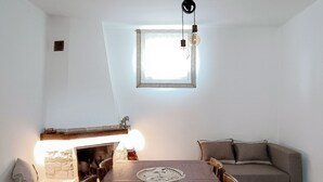 A dining area with a wooden table, chairs, a sofa, and a fireplace. - The House on the Knoll-Valle d'Itria CIN:IT073013C200089627 CIS:TA07301391000050432 (Alberobello)