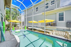A swimming pool with clear water, surrounded by a glass enclosure, and equipped with yellow umbrellas. - Marco Island Family Home: Pool, Lanai, Backyard! (Marco Island)