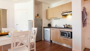 A compact kitchen with a refrigerator, microwave, oven, and a coffee maker.