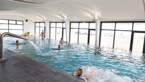 An indoor swimming pool with clear views of the outside through large windows.