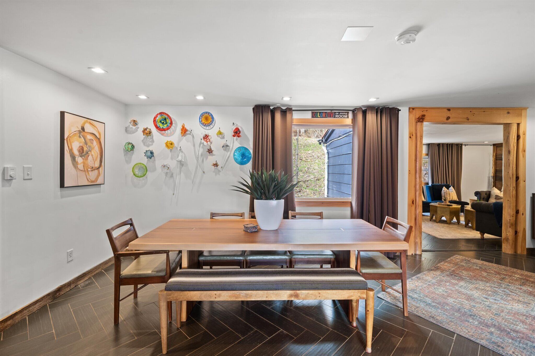A dining area with a wooden table, benches, and a potted plant.
