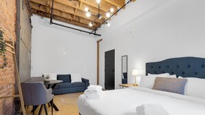 Une chambre d’hôtel moderne avec un grand lit, une petite table, un canapé et un bureau.