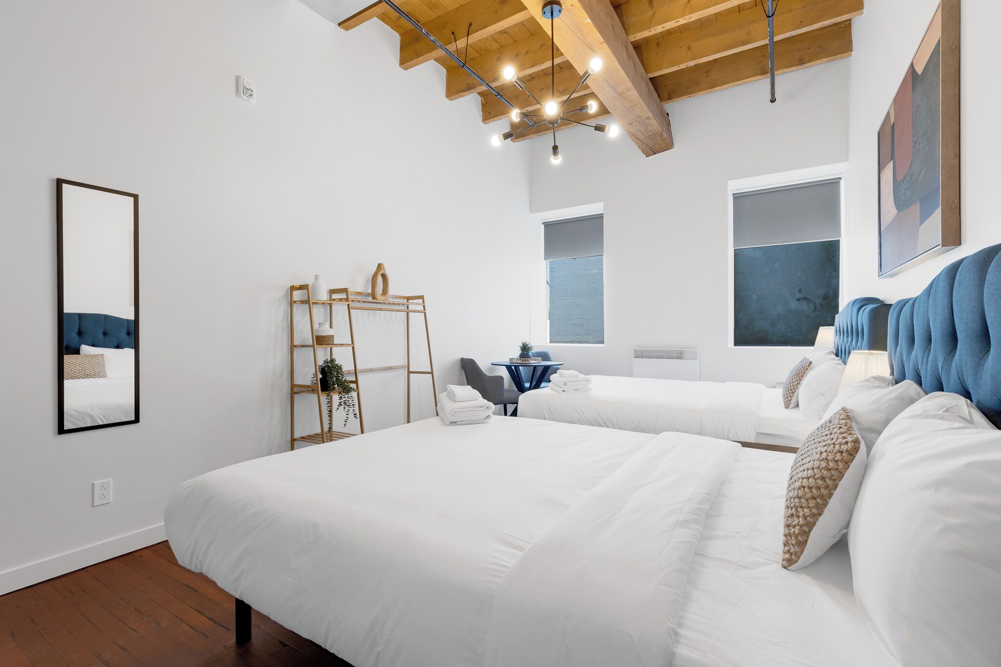 Una habitación de hotel moderna con dos camas, techo de madera, un ventanal grande y un cuadro en la pared.