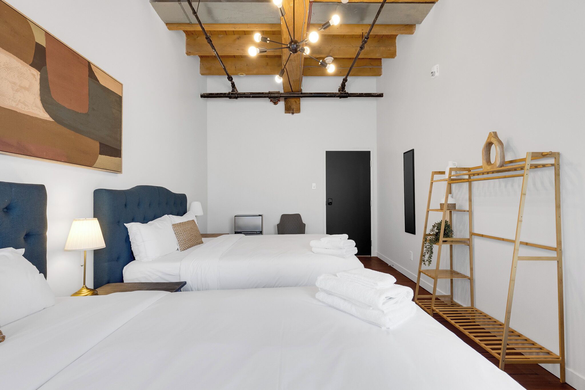 Een hotelkamer met een groot bed, een bureau, een stoel, een televisie en een houten laddenplank.
