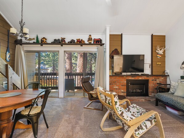 A cozy living room with a fireplace, a television, and a dining area with a table and chairs.