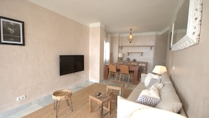A living room with a flat-screen TV, a sofa, a coffee table, and a dining area with chairs and a table. - 170 Tarek Puerto (Tarifa)