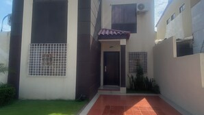 A two-story house with a tiled driveway and a small lawn.
