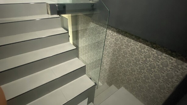 A staircase with glass railings and patterned flooring.