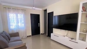 A living room with a sofa, TV, and a white entertainment unit.