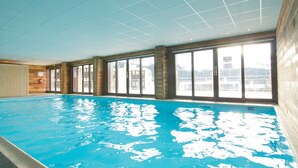 An indoor swimming pool with large windows and wooden walls. - Duplex 6p • Pied des pistes | Jacuzzi & piscine (FLAINE)
