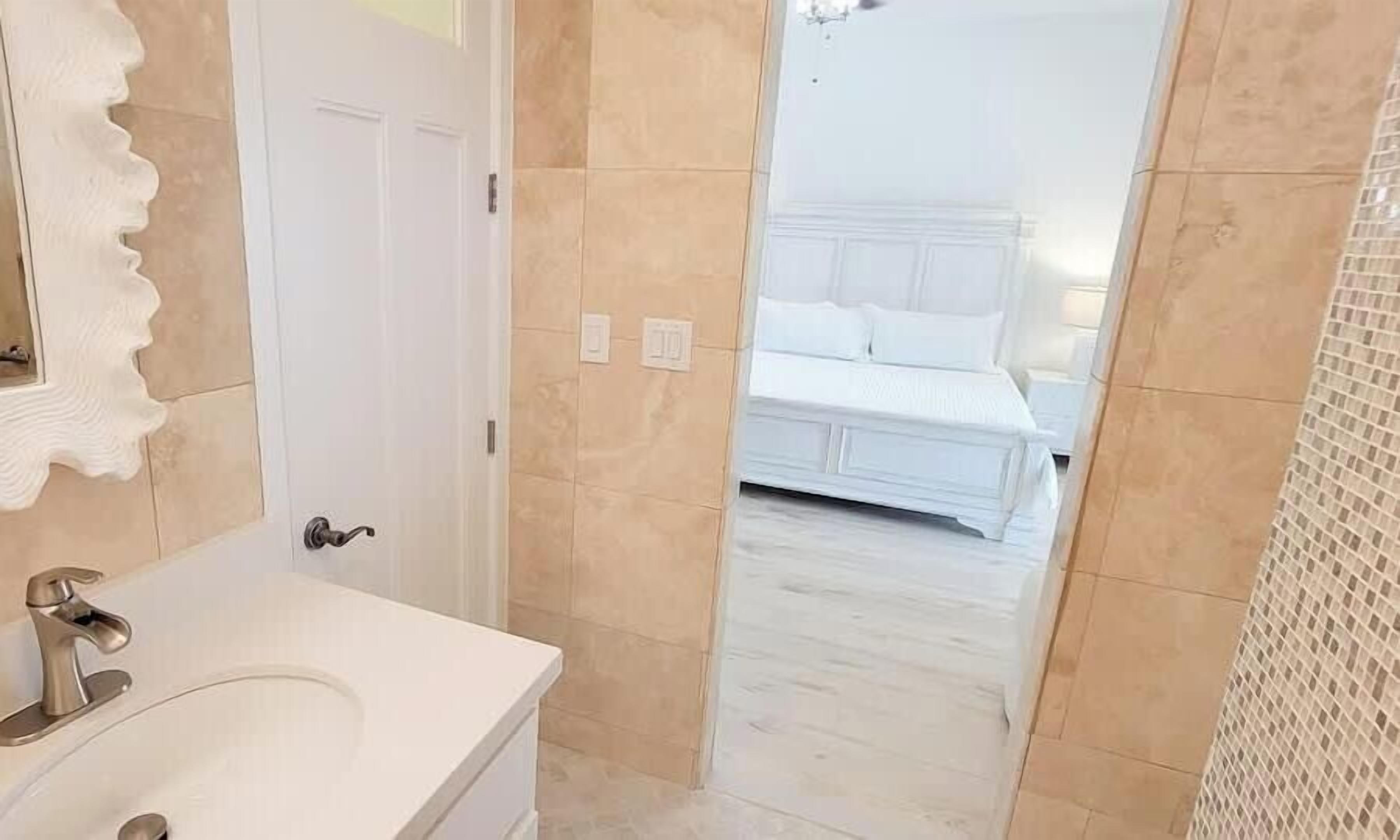 Un baño con un lavabo blanco y un espejo con marco decorativo.