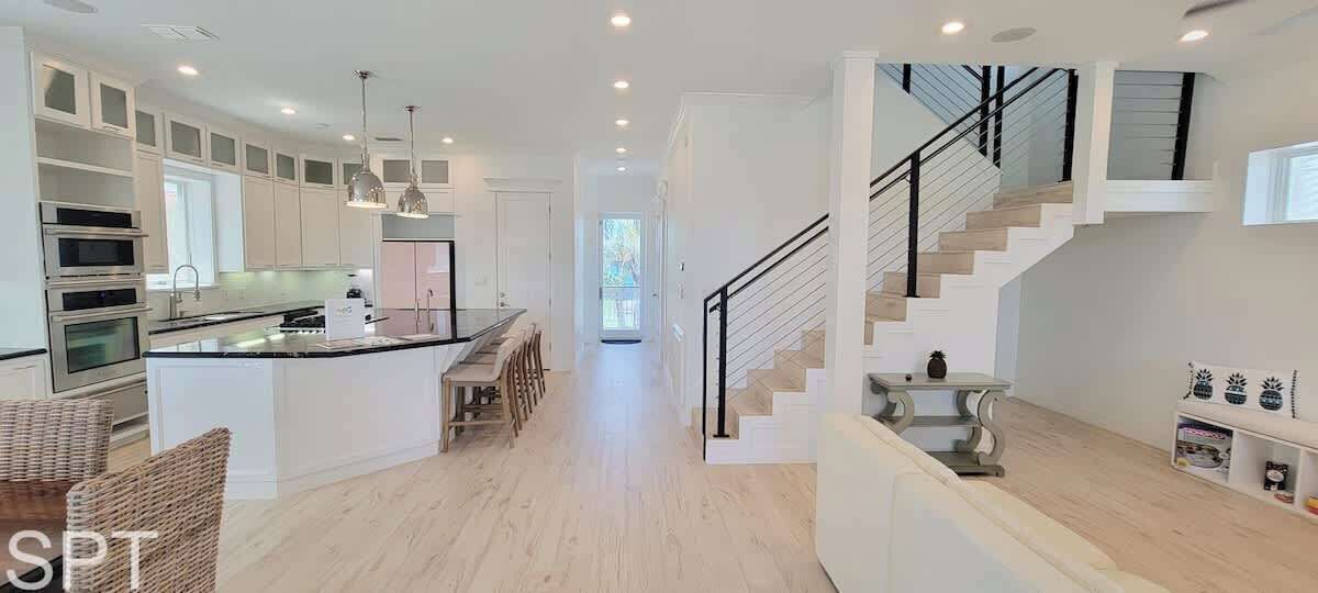 A modern kitchen with a central island, built-in ovens, and a dining area with chairs.