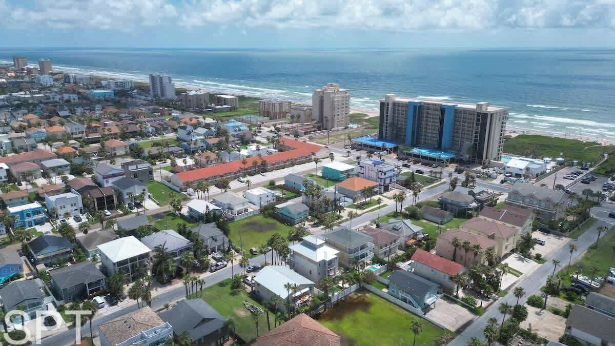 Vista aèria d'una zona residencial costanera amb cases unifamiliars i edificis comercials, incloent un hotel destacat amb façana blava i blanca.
