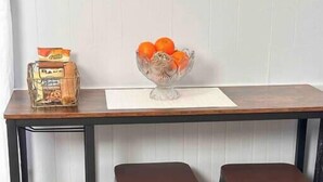 A dining table with two stools, a glass bowl with oranges, and a bag of bread on the left side. - 4 bedroom parking ,washer & dryer Apt (New York)