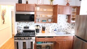 A modern kitchen with wooden cabinets, a stainless steel stove, a microwave, and a built-in oven. - 4 bedroom parking ,washer & dryer Apt (New York)