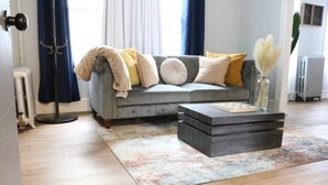 A living room with a grey sofa, a dark coffee table, and a colorful rug. - 4 bedroom parking ,washer & dryer Apt (New York)