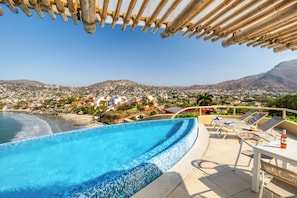A poolside area with a view of a beach and town. - Villas Kaukan by Tasman (Zihuatanejo)
