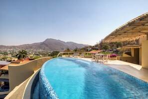 A swimming pool with a view of mountains, lounge chairs, and a patio area. - Villas Kaukan by Tasman (Zihuatanejo)