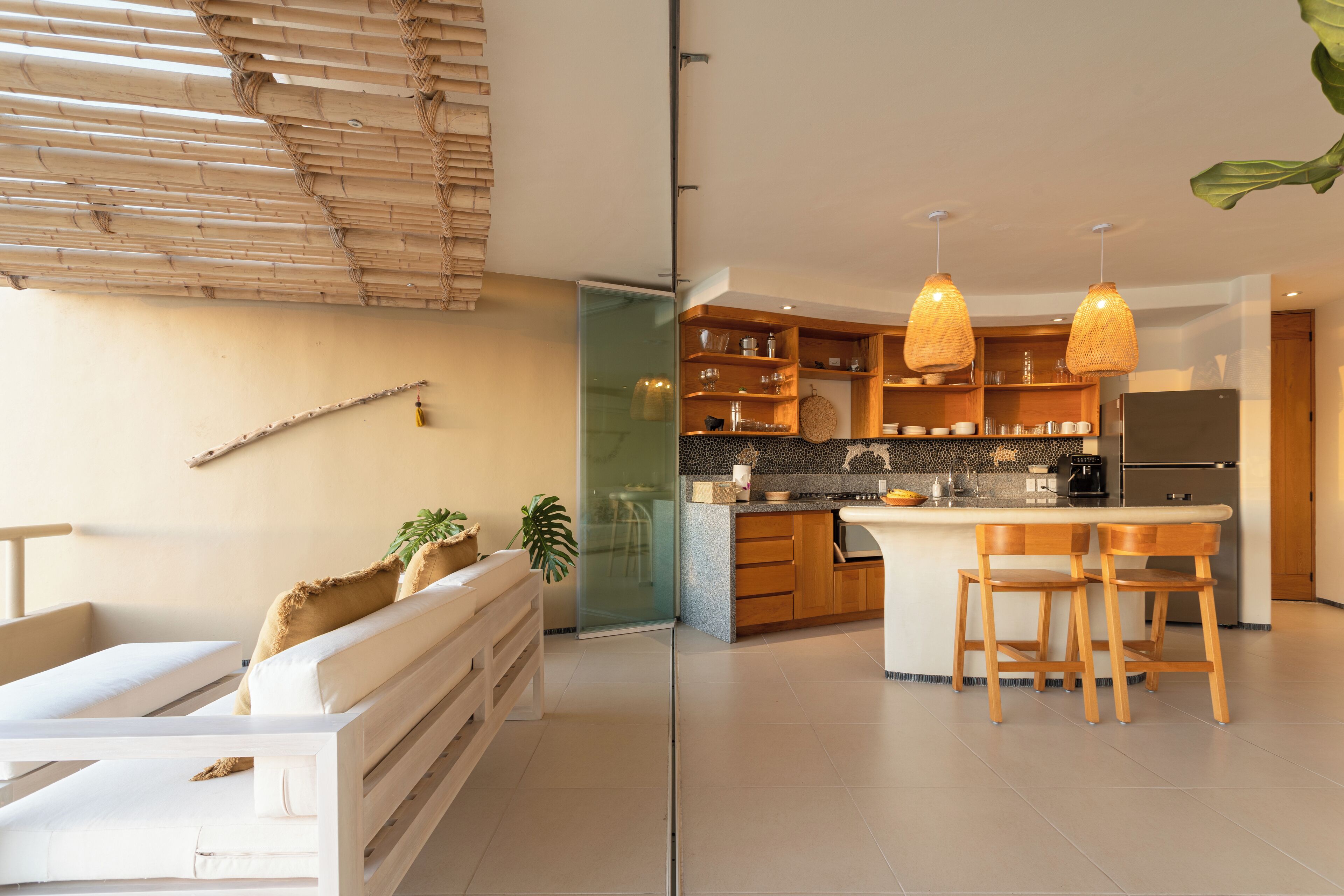 Une cuisine moderne avec des meubles en bois, un îlot central doté de tabourets de bar et un éclairage suspendu.