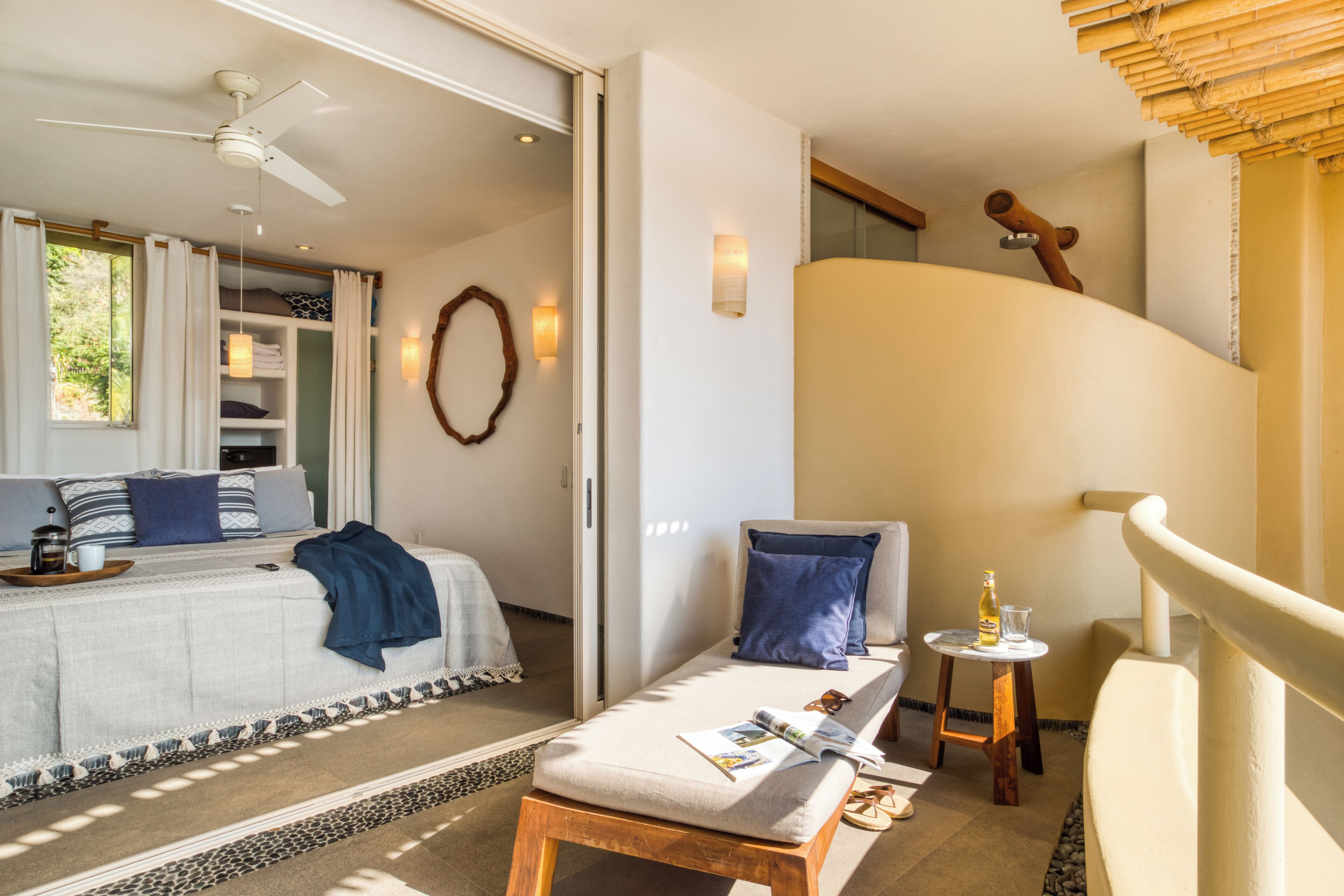 Une chambre d’hôtel moderne avec un lit, un coin lecture, une petite table avec une bouteille et un escalier.
