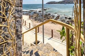 A staircase leading to a beach with rocky terrain and a view of the sea. - Villas Kaukan by Tasman (Zihuatanejo)