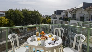Een balkon met een ontbijt aan tafel, inclusief croissants, sinaasappelsap en een krant.